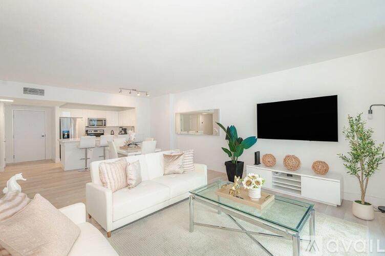A living room with a white couch and a glass coffee table.