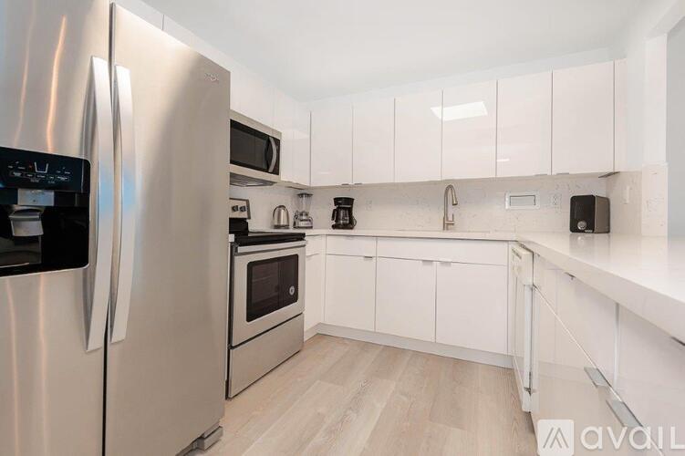 A modern kitchen with a stainless steel refrigerator and white cabinets.