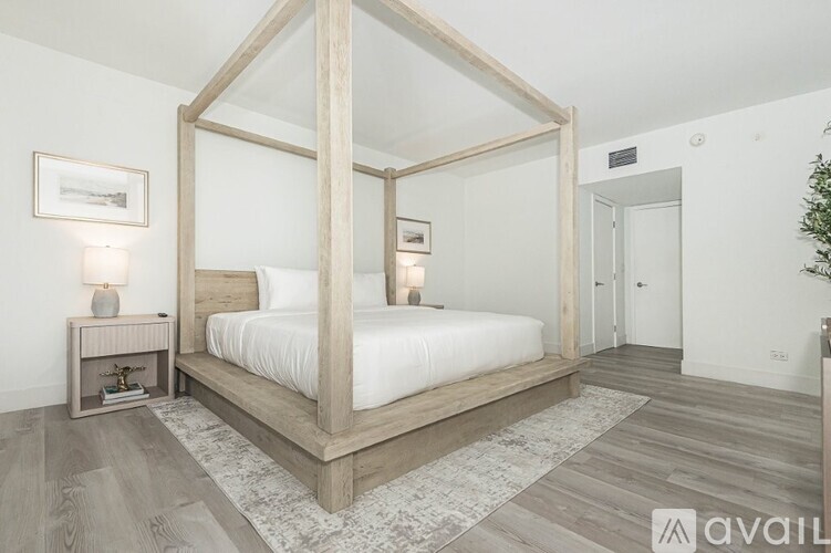 A bedroom with a four poster bed and a nightstand with a lamp.