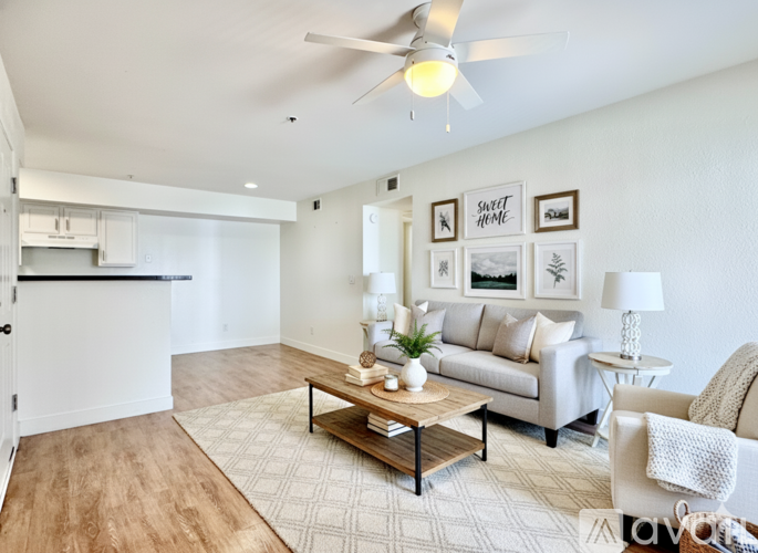 A living room with a white couch, a coffee table, and a ceiling fan.