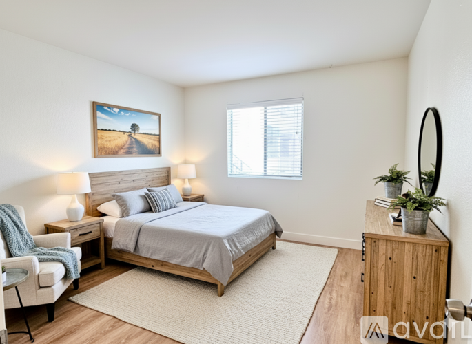 A bedroom with a bed, chair, and a painting on the wall.