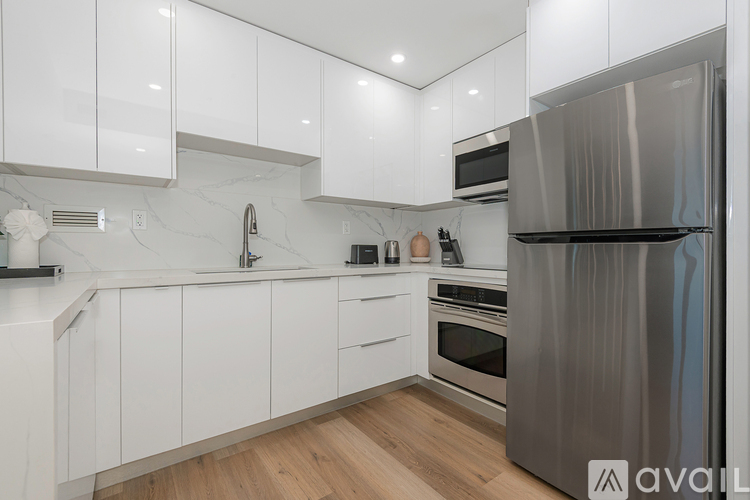 A modern kitchen with white cabinets and a stainless steel refrigerator.