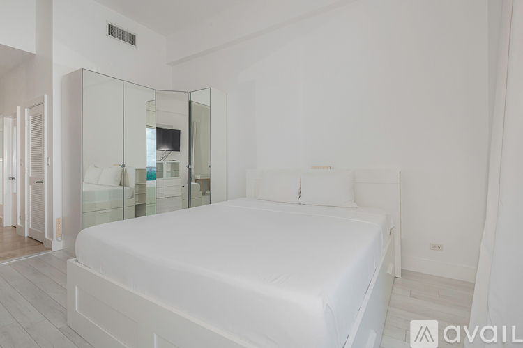 A bedroom with a large bed and a glass walled shower.