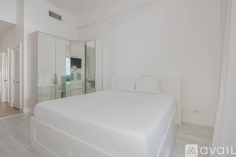 A bedroom with a large bed and a glass walled shower.