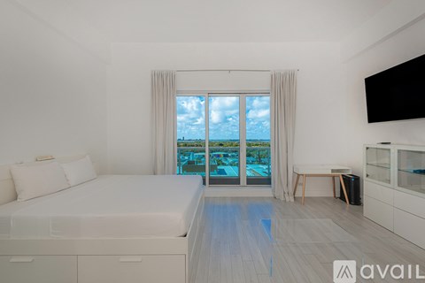 A bedroom with a large bed and a view of the pool through the window.