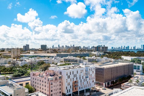 A cityscape with a mix of modern and older buildings under a blue sky with clouds.