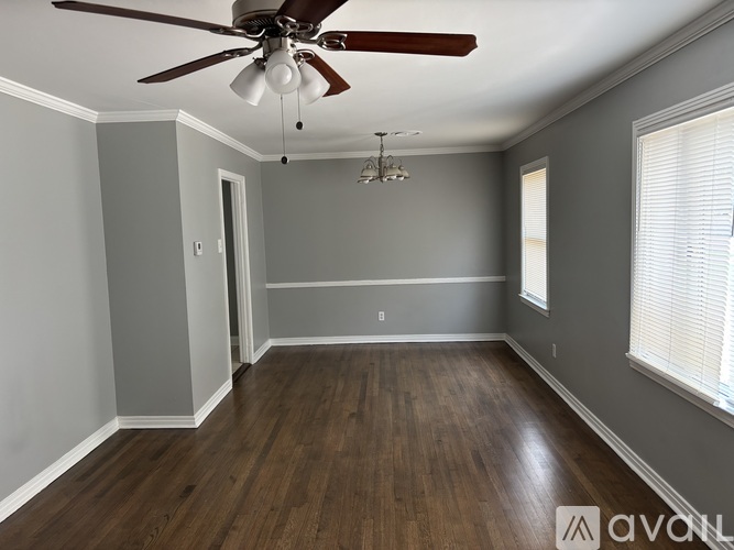 A room with a ceiling fan and wooden flooring.