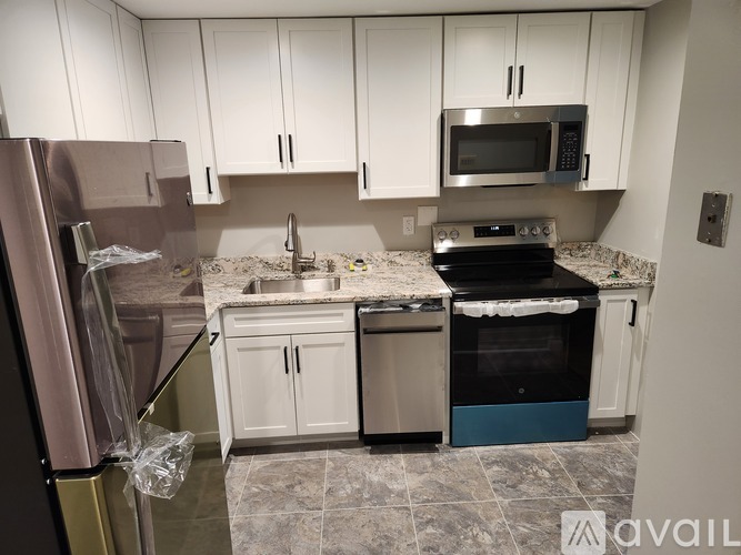 A kitchen with white cabinets and a refrigerator.