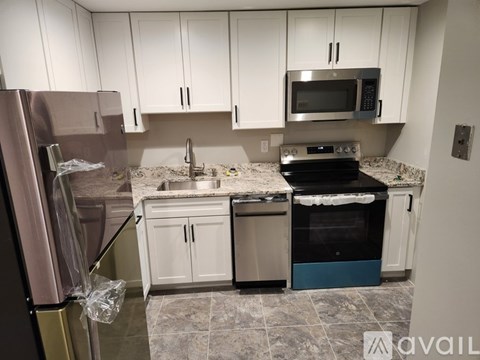 A kitchen with white cabinets and a refrigerator.