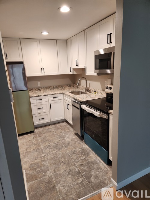 A kitchen with white cabinets and a tiled floor.