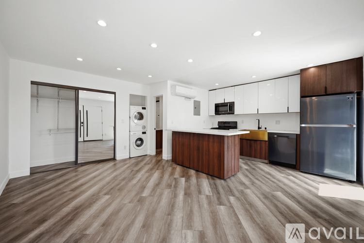 A modern kitchen with wooden floors and stainless steel appliances.
