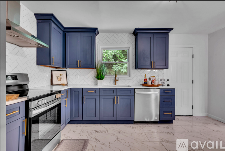 A kitchen with dark blue cabinets and a white tiled backsplash.