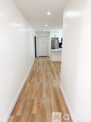 A hallway with wooden floors and white walls.