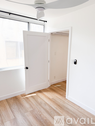 A room with a white door and a fan on the ceiling.