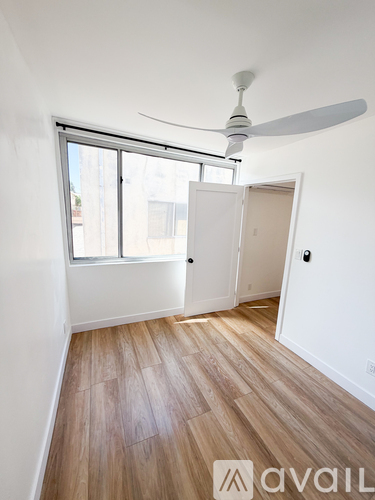 A room with a fan and a door leading to another room.