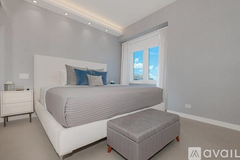 A bedroom with a large bed and a small ottoman.