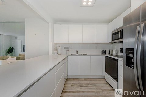 A kitchen with white cabinets and a stainless steel refrigerator.