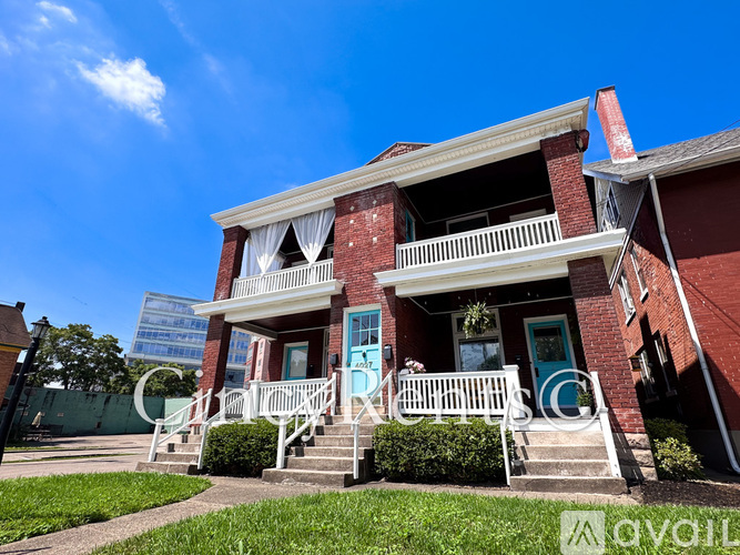 A red brick house with a blue door and white railings.