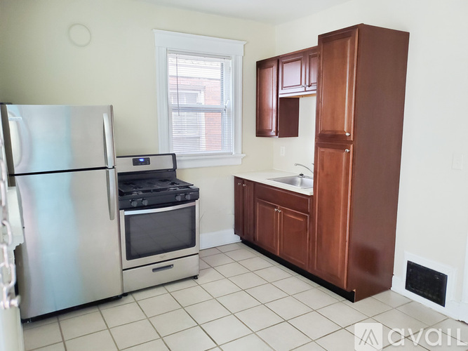 A kitchen with a stainless steel refrigerator and wooden cabinets.