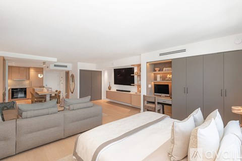 A modern bedroom with a large bed and a living area with a couch and a television.