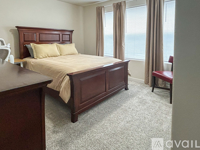 A bedroom with a large bed and a window with curtains.