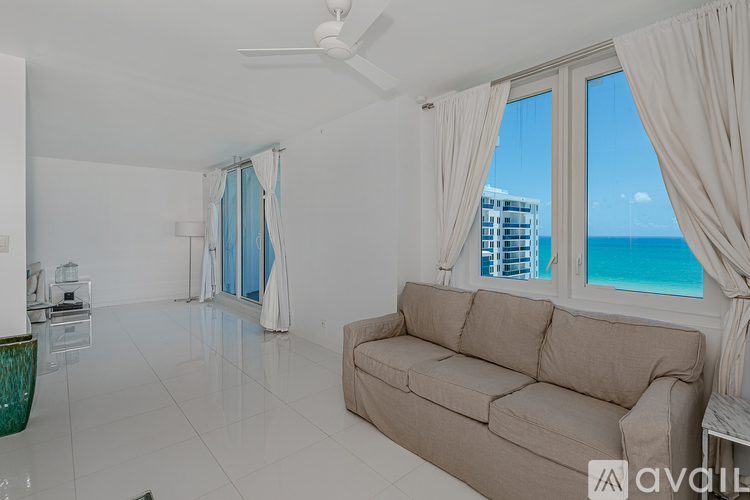 A living room with a couch and a view of the ocean through the window.