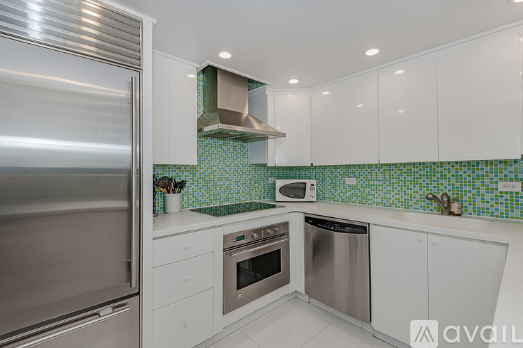 A modern kitchen with white cabinets and a stainless steel refrigerator.