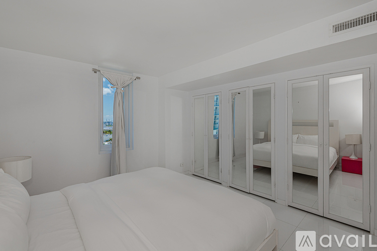 A bedroom with a large bed and a window with curtains.