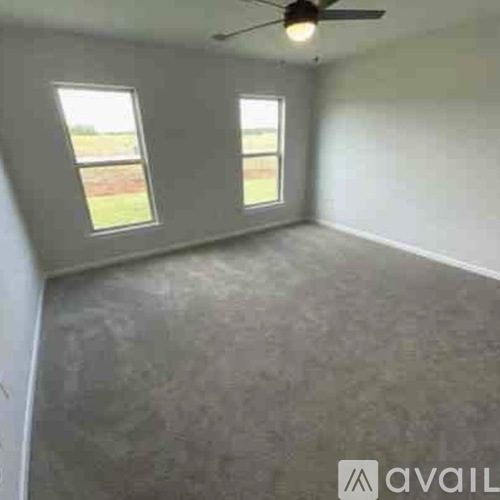 A room with a ceiling fan and two windows.
