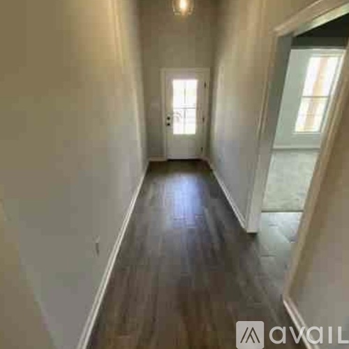 A long hallway with wood floors and white walls.