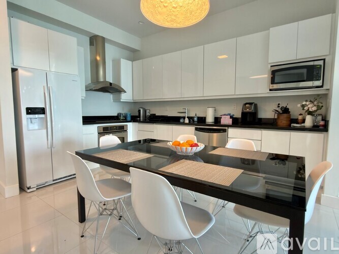 A modern kitchen with a black table and white chairs.