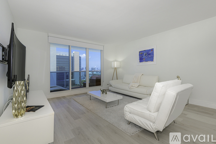 A living room with a white couch and a television on the wall.