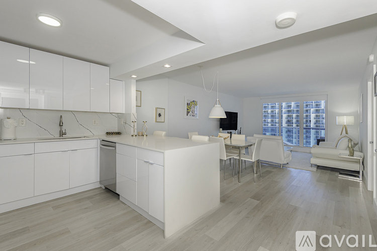 A modern kitchen with white cabinets and a wooden floor.