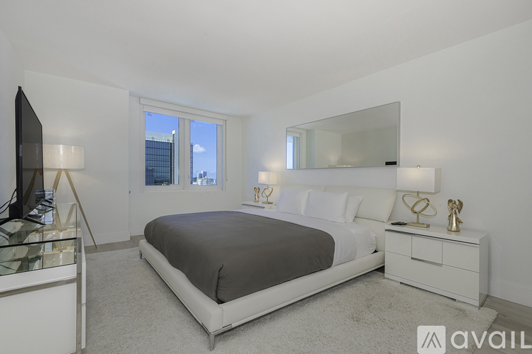 A bedroom with a large bed, a dresser, and a mirror.