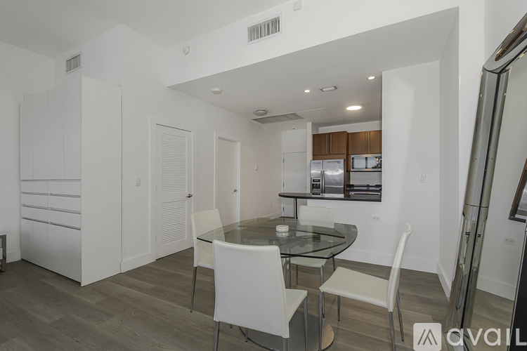 A modern kitchen with a glass table and white chairs.
