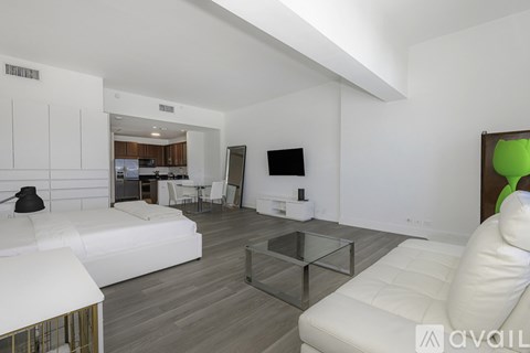 A modern living room with white furniture and a glass coffee table.