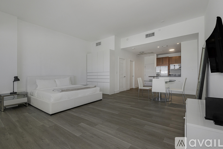 A modern bedroom with a large bed and a separate dining area.