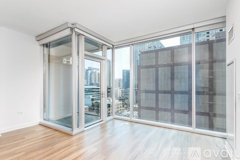 A room with a wooden floor and a glass door leading to a balcony with a city view.