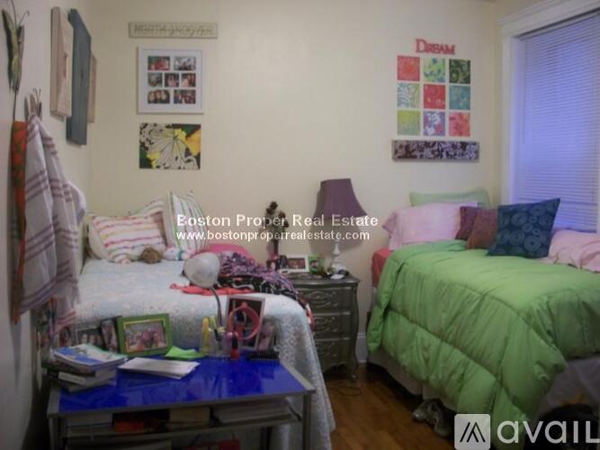 A bedroom with a bed, a nightstand, a table, and a wall hanging.