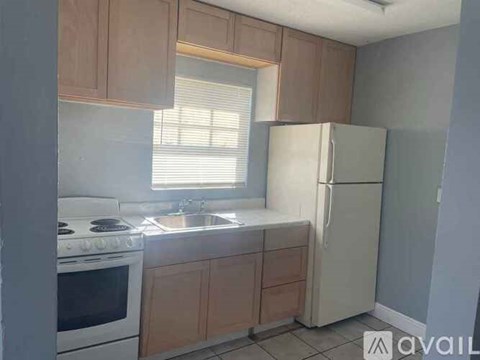 A kitchen with a white fridge, stove, and sink.