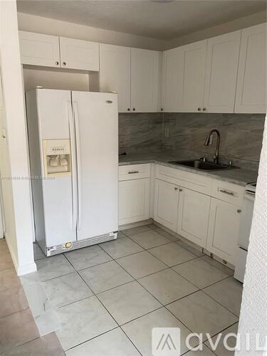 A kitchen with a white stove, sink, and cabinets.