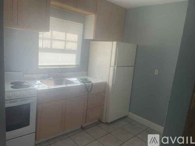 A kitchen with a stove, sink, and refrigerator.