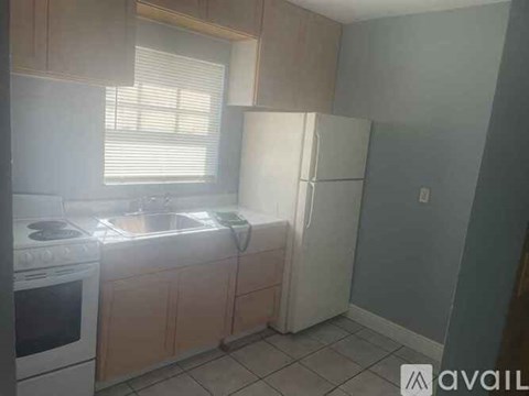 A kitchen with a stove, sink, and refrigerator.