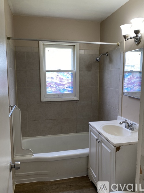 A bathroom with a tub, sink and window.
