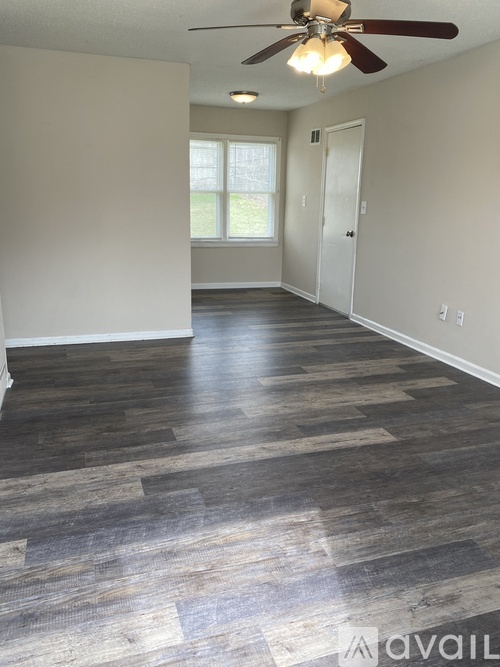 A room with a ceiling fan and wooden flooring.