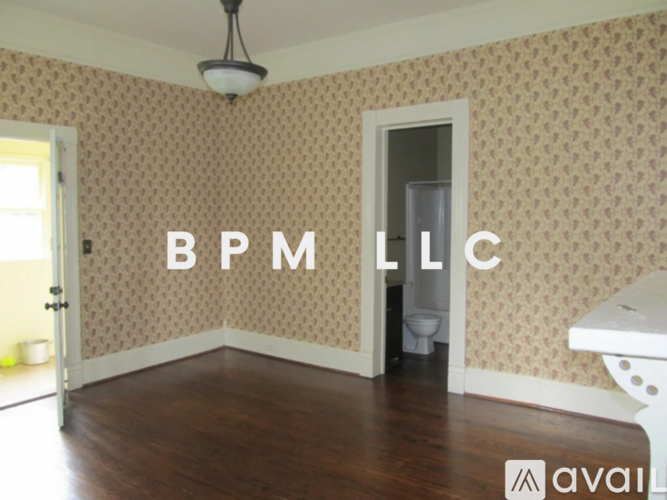 A room with a toilet and a sink with the letters BPM LLC on the wall.