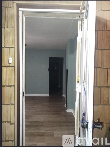 A hallway with a door on the right and a wall on the left.