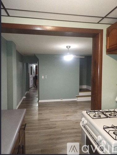 A kitchen with a stove top oven and a doorway leading to another room.