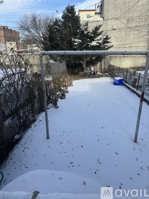 A snow-covered ground with a fence and a tree in the background.