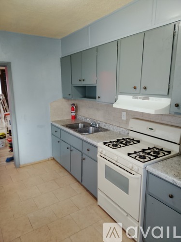 A kitchen with a white stove and grey cabinets.